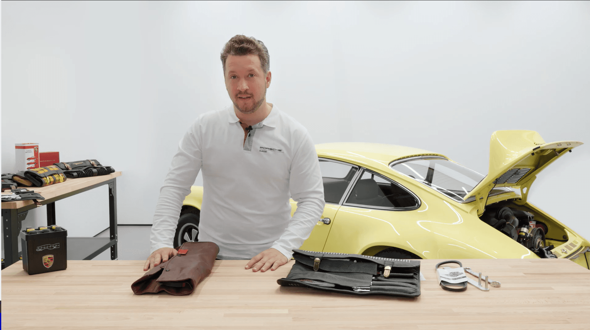 man is standing at a table with a Porsche Classic tool kit on it