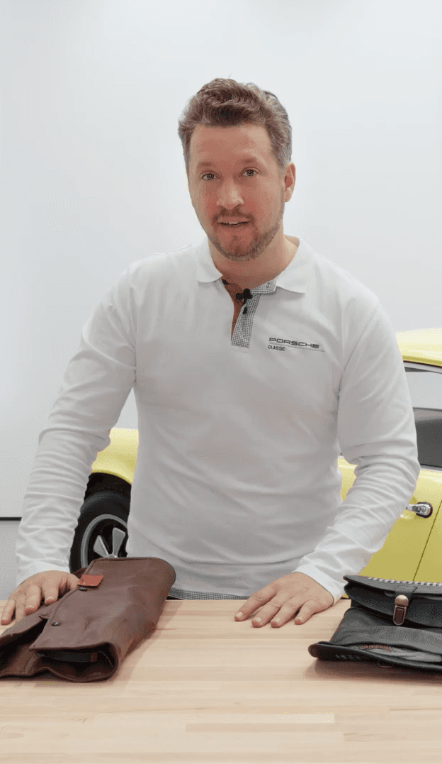 man is standing at a table with a Porsche Classic tool kit on it