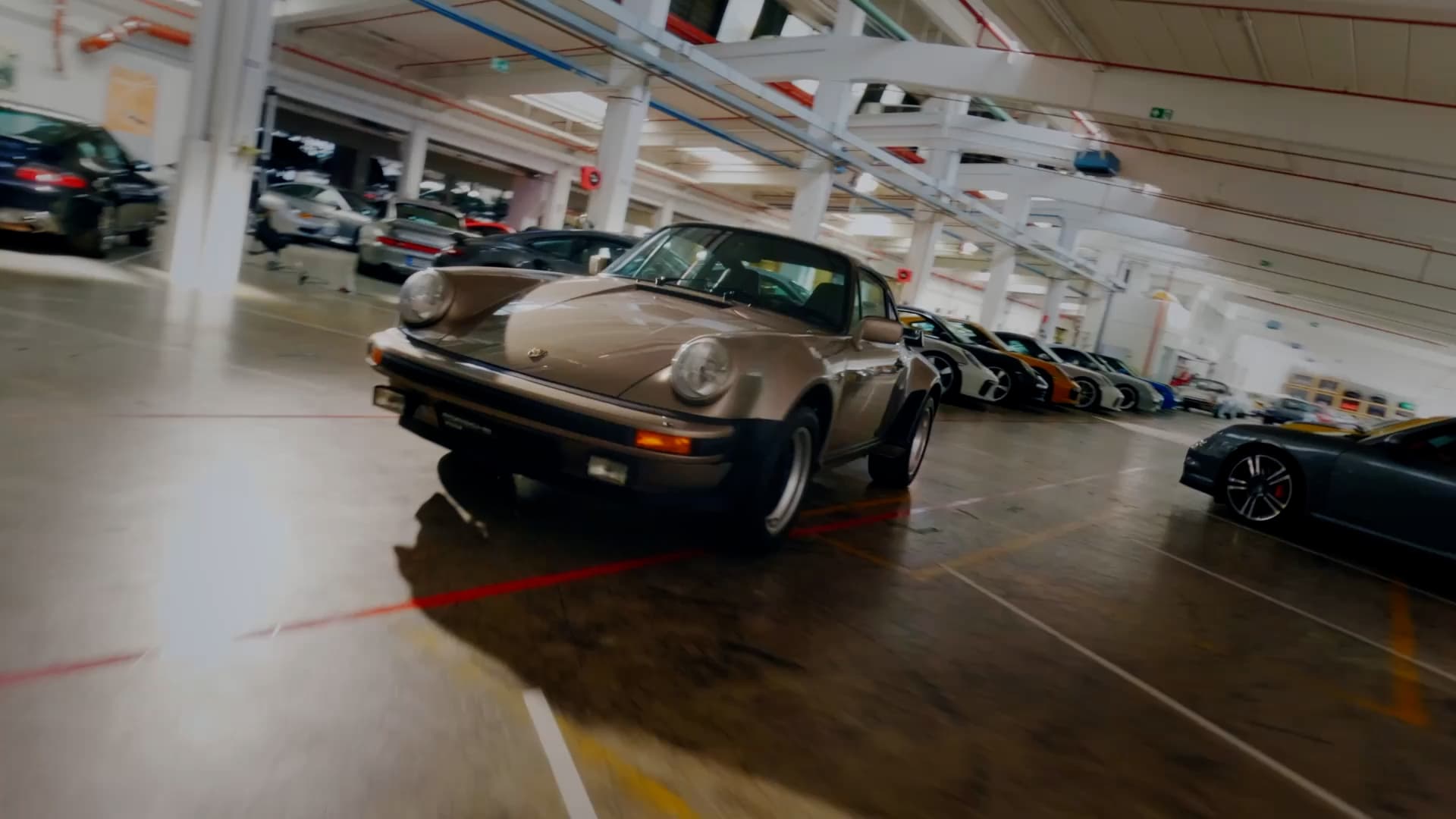 A historic Porsche 911 is driving through a garage
