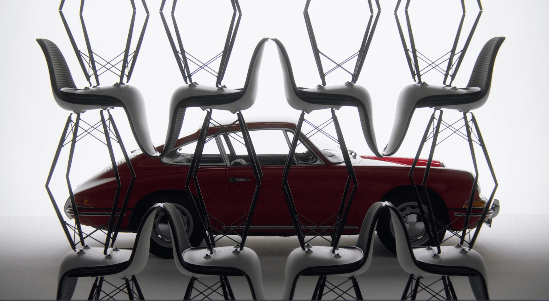 Few Vitra for Porsche Eames chairs in front of a red historic Porsche 911