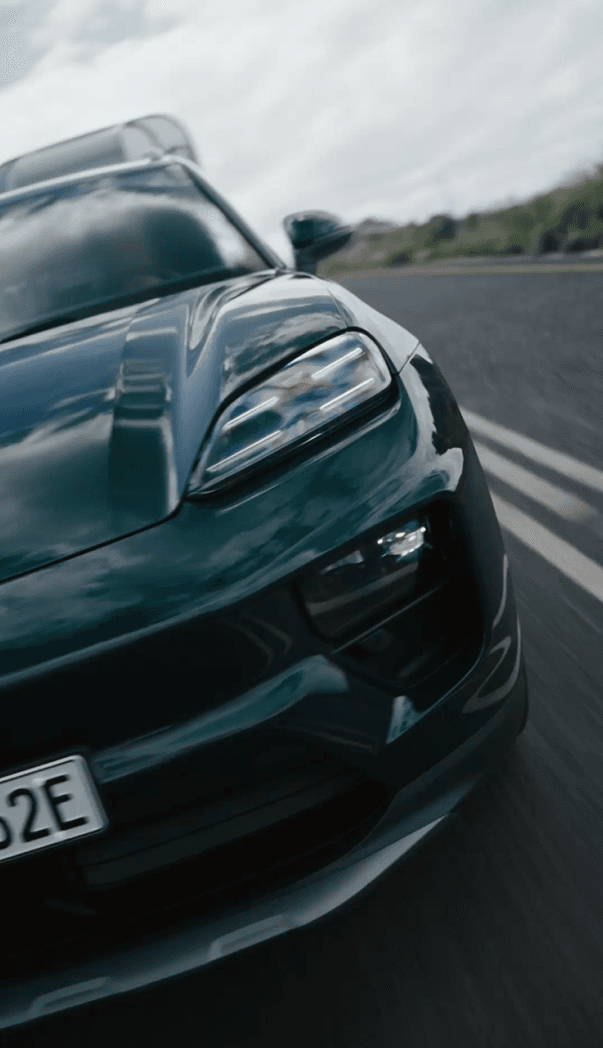 close up of an oakgreen Porsche Macan from the front on a street
