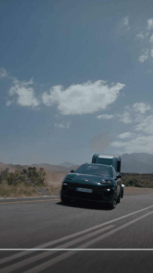 an oakgreen Porsche Macan is driving on a street