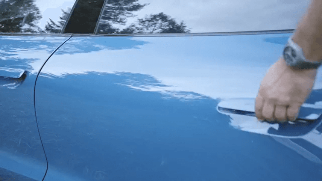 A person is opening the door of a blue Porsche car