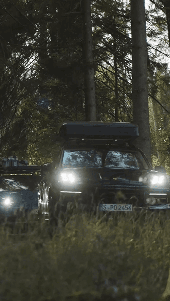 Two Porsche cars driving through the forest