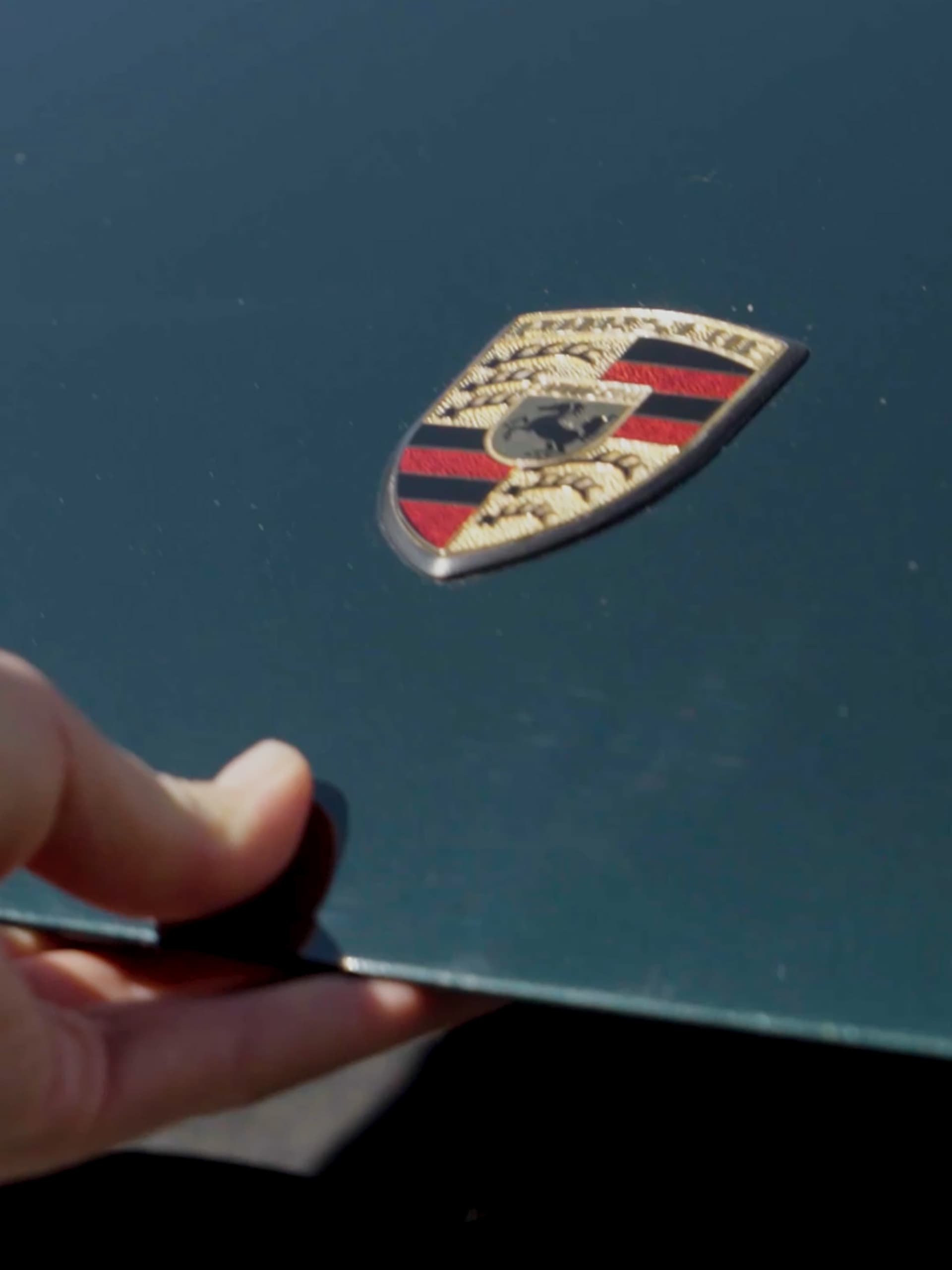 Een persoon opent de kofferbak van een Porsche 911.